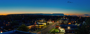 A cityscape at dusk with buildings and streets illuminated.